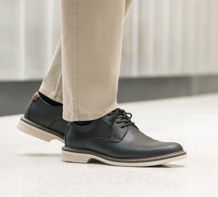 Shop Florsheim top sellers featuring the Norwalk plain toe oxford in black next to a gray building. 