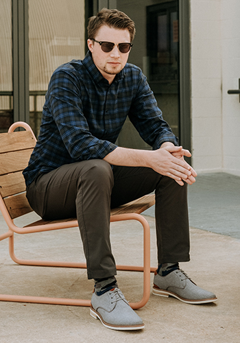 Image of social media influencer Matt Hartman wearing the Highland Plain Toe Canvas Oxford in Gray while sitting in a chair outside.