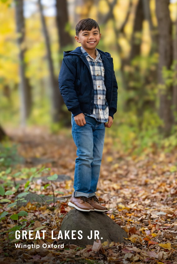 Kids Shoes view all category Image features a child wearing the Great Lakes Junior Wingtip Oxford in a forest setting.