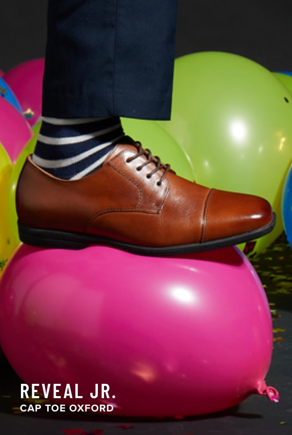 Boy's Dress Shoes category. Image features the Reveal Jr. Cap Toe Oxford in cognac.