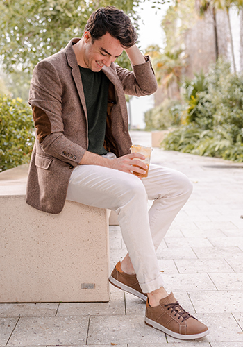 Image of social media influencer Alessandro Pontes sitting outside in the Crossover Lace To Toe Sneaker in Mushroom.